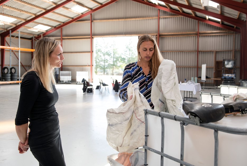 Medindehaver af Salling Autoophug, Lise Korsgaard i en fabrikshal sammen med en kvinde, der kigger på materialer fra biler. Foto: Salling Autoophug